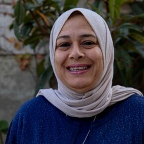 Hadeel Qazzaz sourit dans une tenue bleu foncé avec un hijab gris clair.